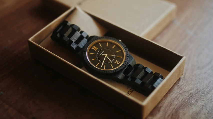 a black and gold watch in a cardboard box