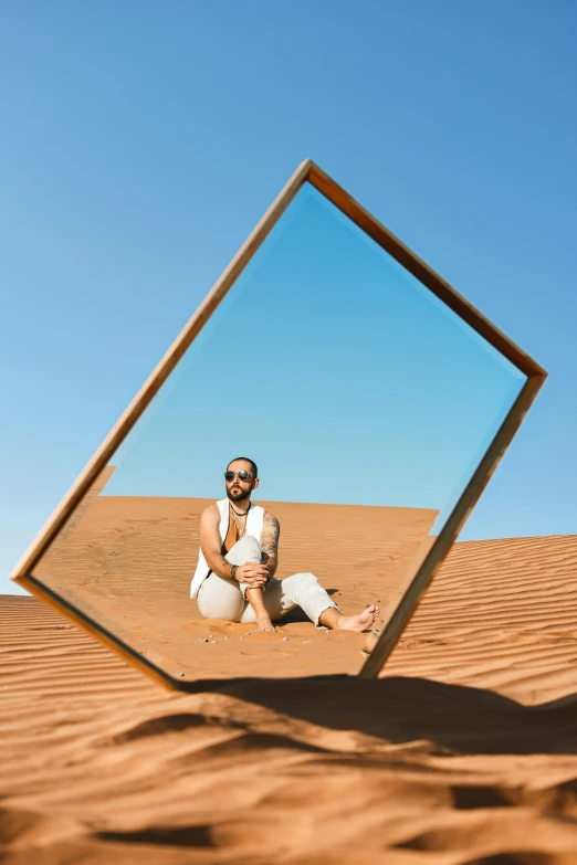 man sitting in the desert wearing all white