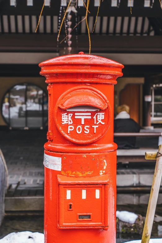 a red post box stands outside an asian house