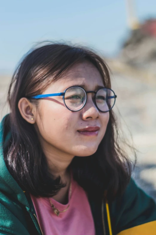 a woman with glasses on standing next to a building