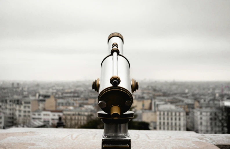 a telescope on top of a building with a city in the background