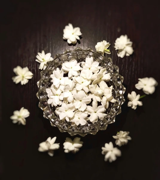 white petals floating in a glass bowl on a wooden surface