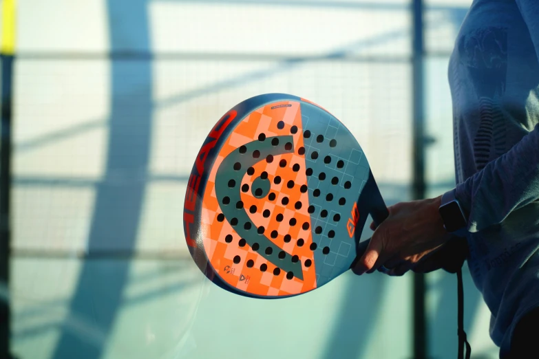 a person holding an orange and gray paddle