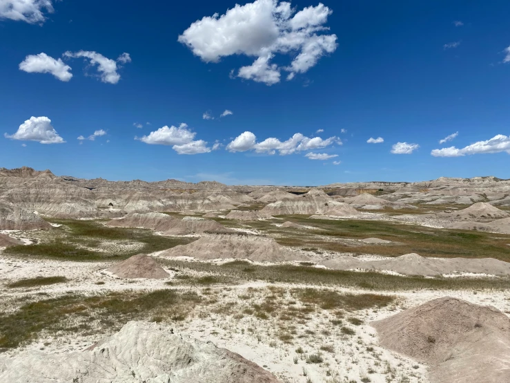 an outcropping of sandy and barren desert under a cloudy blue sky