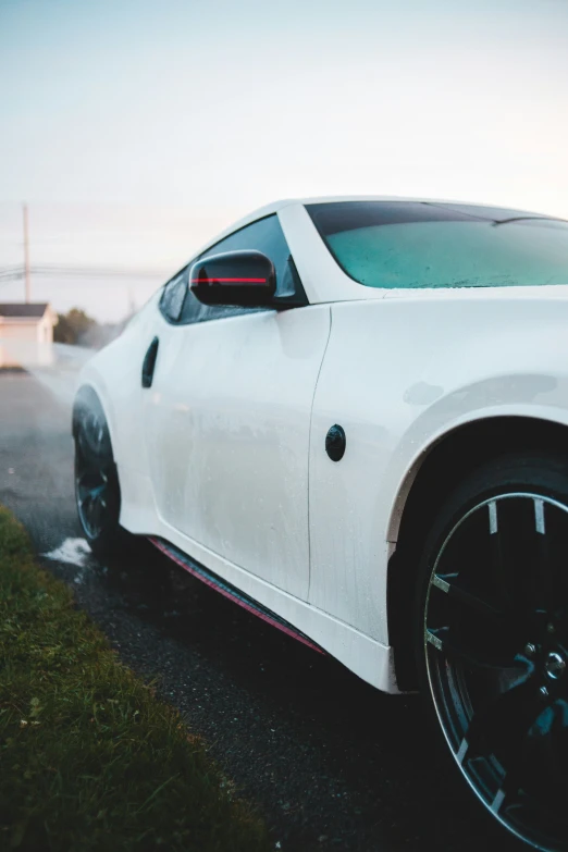 the white sports car is parked near the grassy area