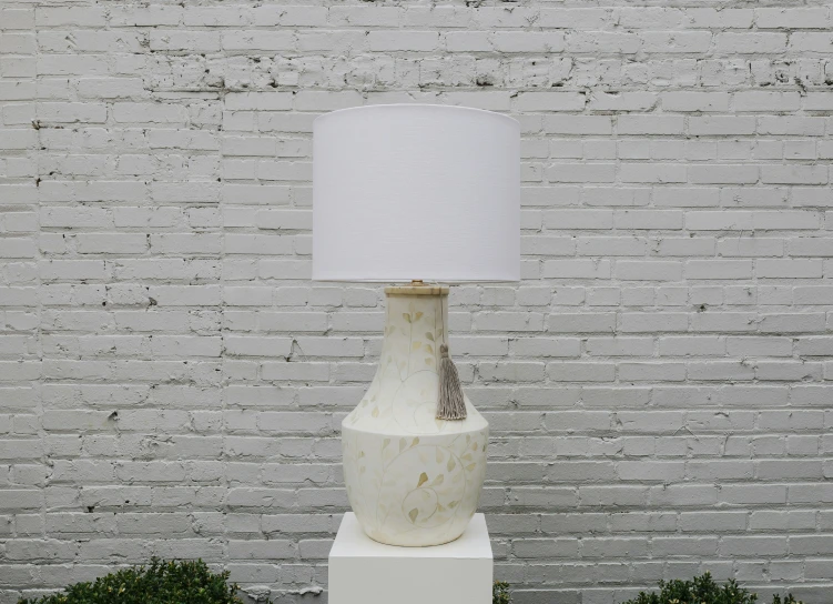 the light on the marble lamp stands next to the white brick wall