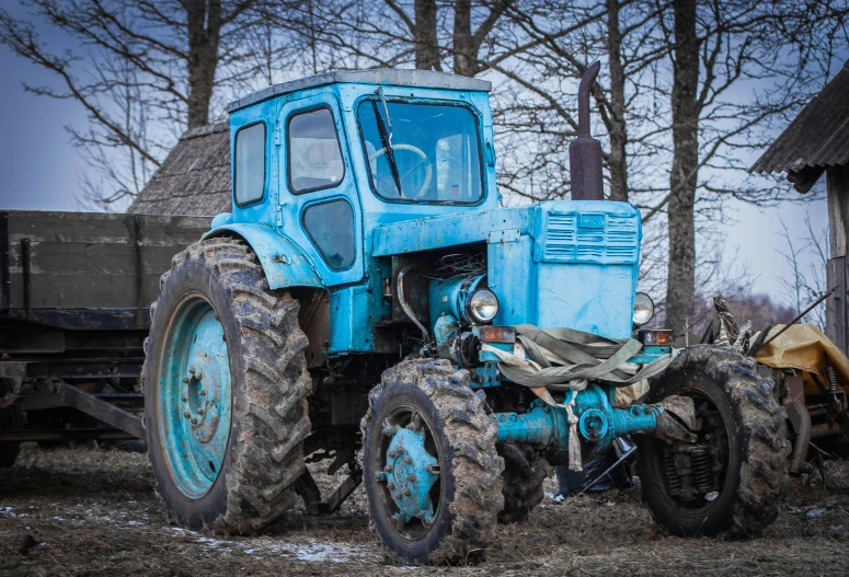 an old blue tractor is sitting on the side of the road