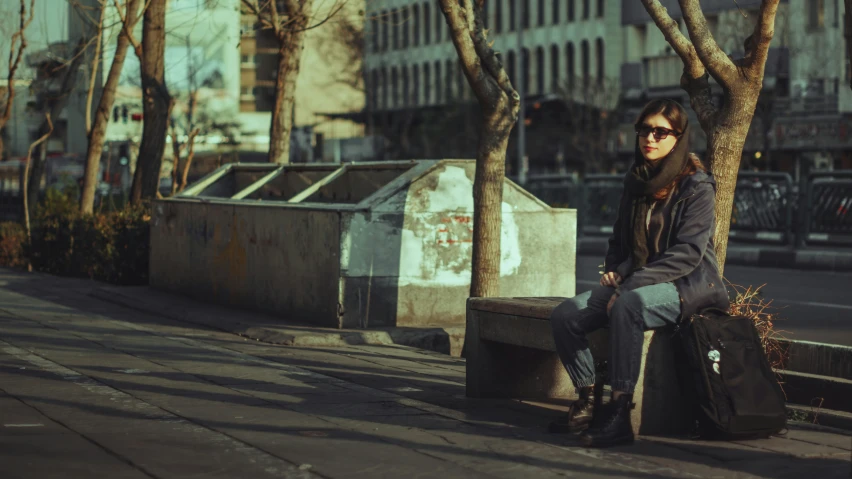 a woman sitting on a park bench holding her suitcase