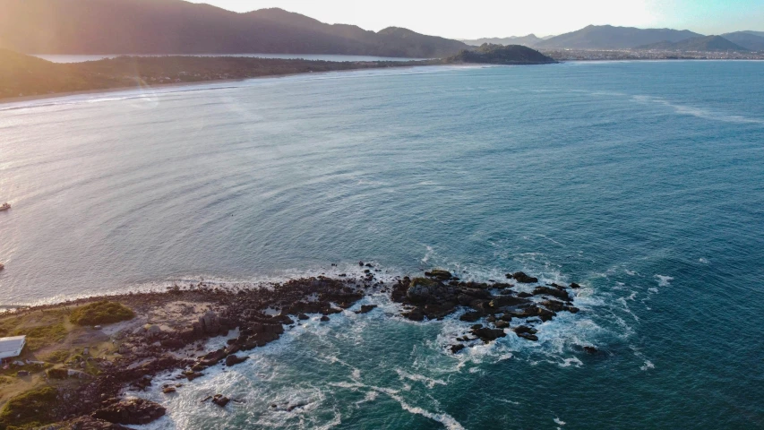 an aerial po of the ocean with a boat sailing in it