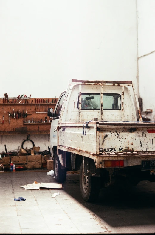 a rusted white pick up truck and wall of wood