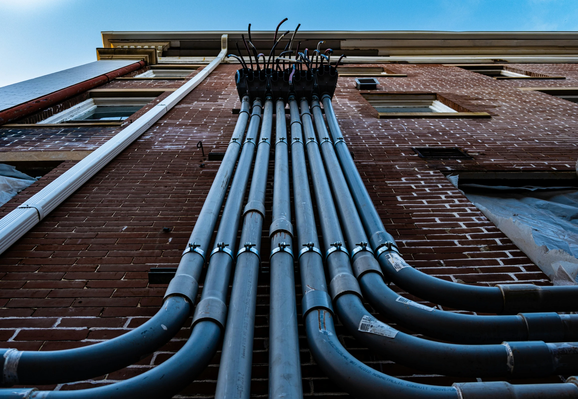 the side of a building with multiple drainage pipes on each of it