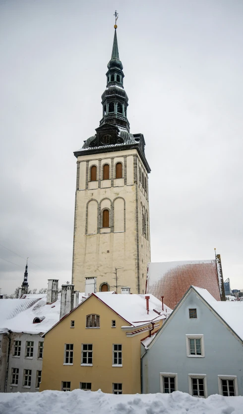 the church tower towering above many other buildings on a snowy day