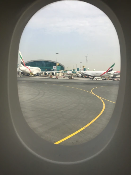 looking out the window of an airplane to the airport with the planes