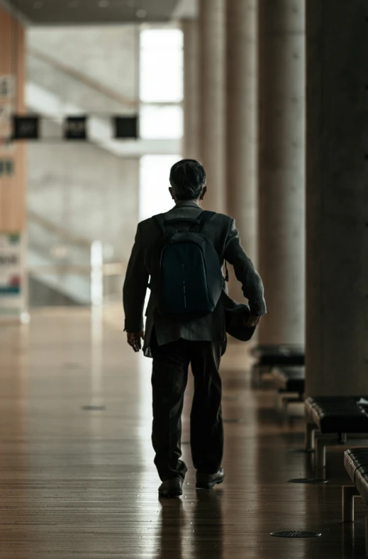 a man is walking in a hall with backpack