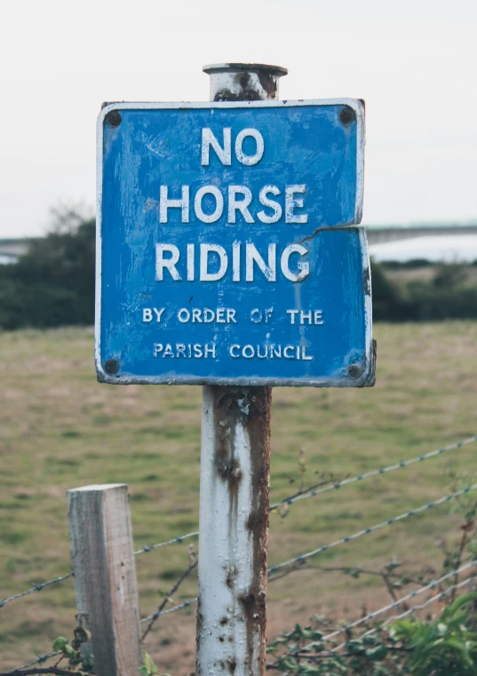 a blue sign is hanging on a chain link fence