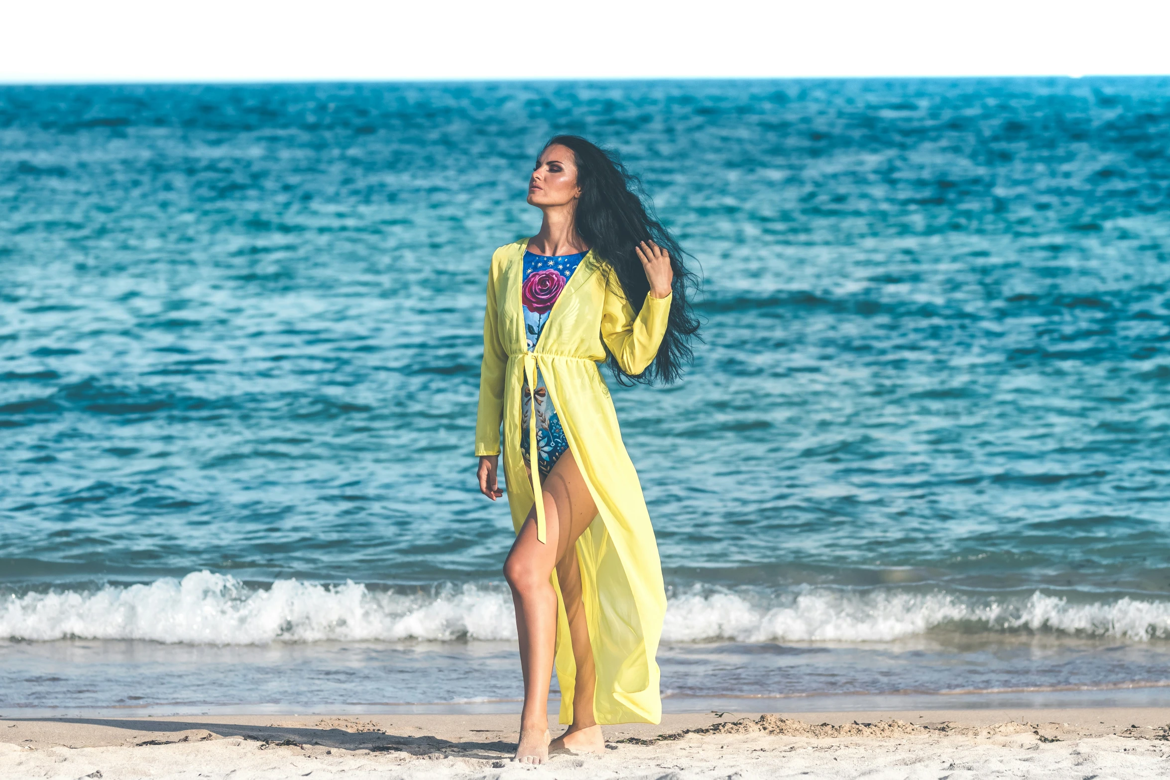 the woman is standing on the beach by the ocean