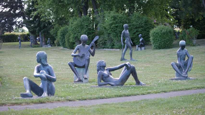 statues sit in the park as people play guitar