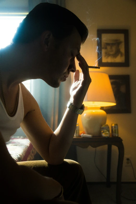 a man sitting down smoking a cigarette in the dark