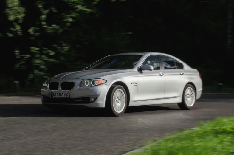 a silver car on a road with trees in the background