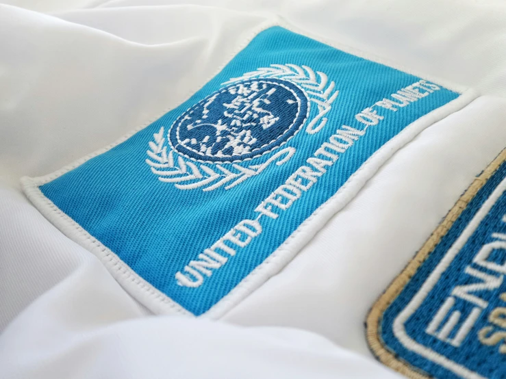 the logo on a white jacket with a blue and gold emblem