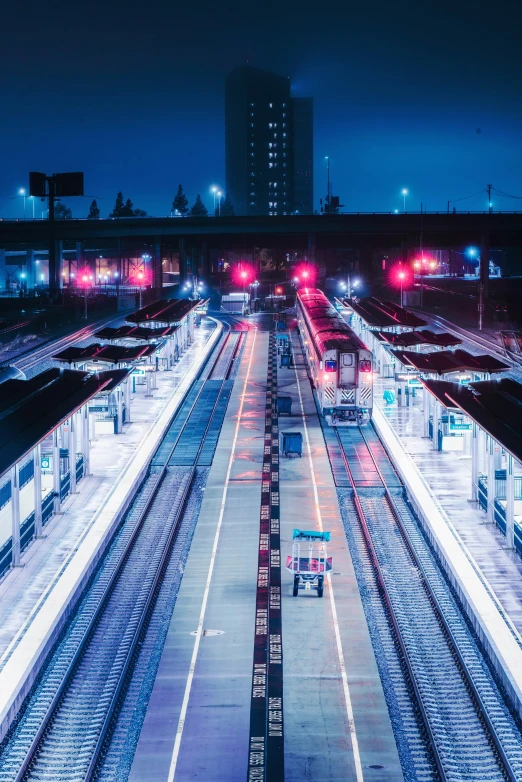 several different train tracks next to buildings at night