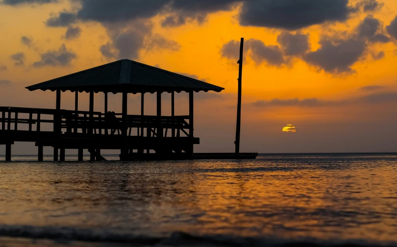 an umbrella on top of a wooden dock at sunset