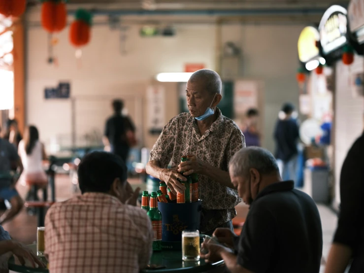 men are at the dining tables and there is a man on a cell phone