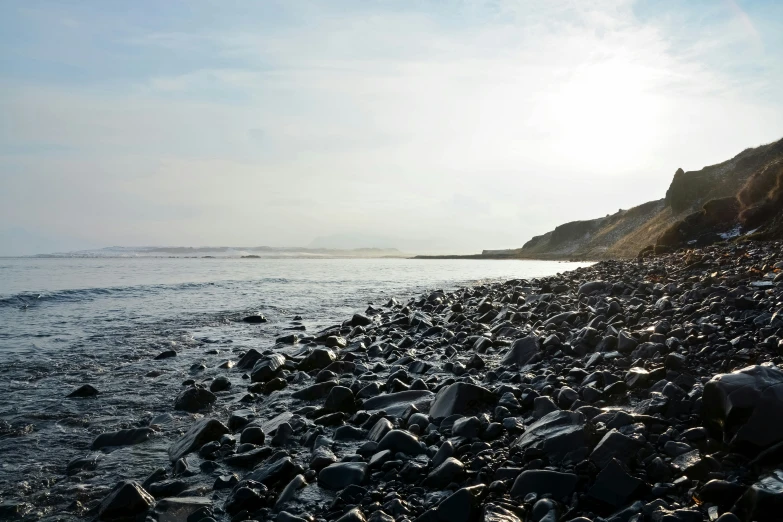 the sun is setting over a rocky shore