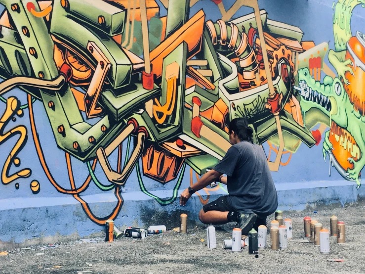 man sitting on top of a stool in front of a graffiti wall