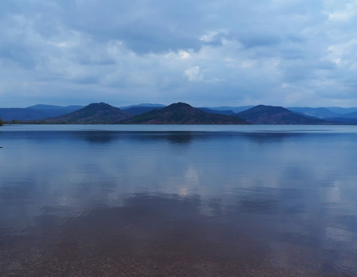 water with mountains in the background on a cloudy day