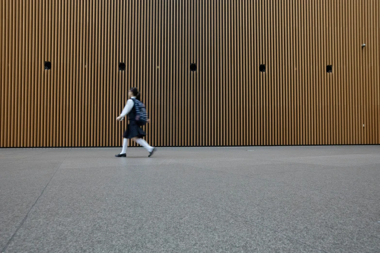 a person walking past a wall near a clock