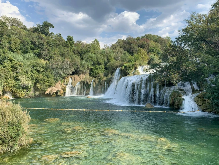 a waterfall with a lake surrounded by trees