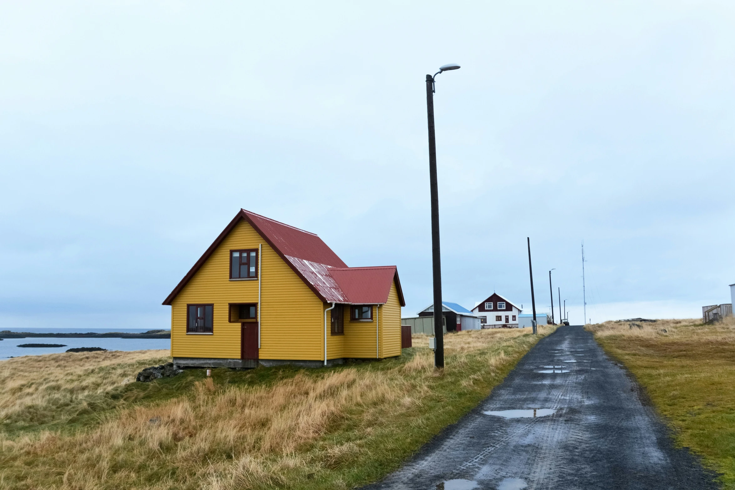 a yellow house is in the middle of an empty road