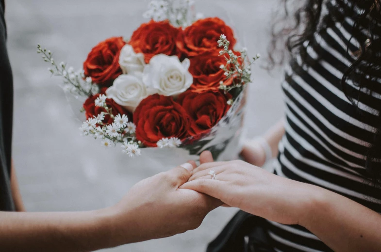 two women holding hands with red and white roses