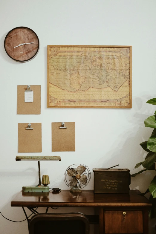 an old map hung above a desk next to two plant