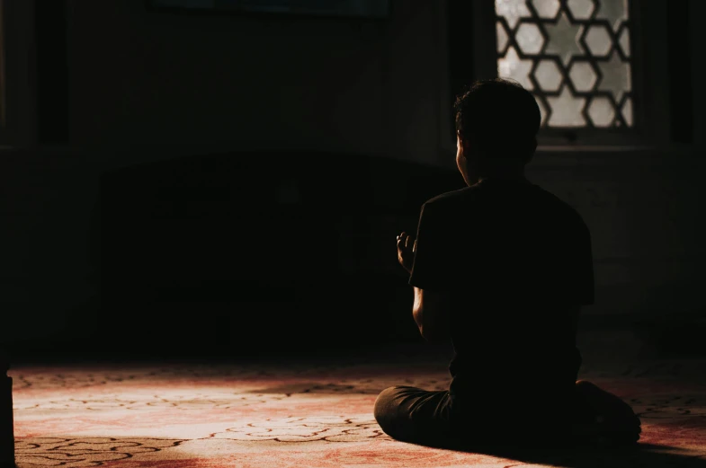 a man sitting on the floor and a window near by