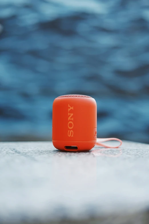 an orange sony camera sits on top of a concrete wall