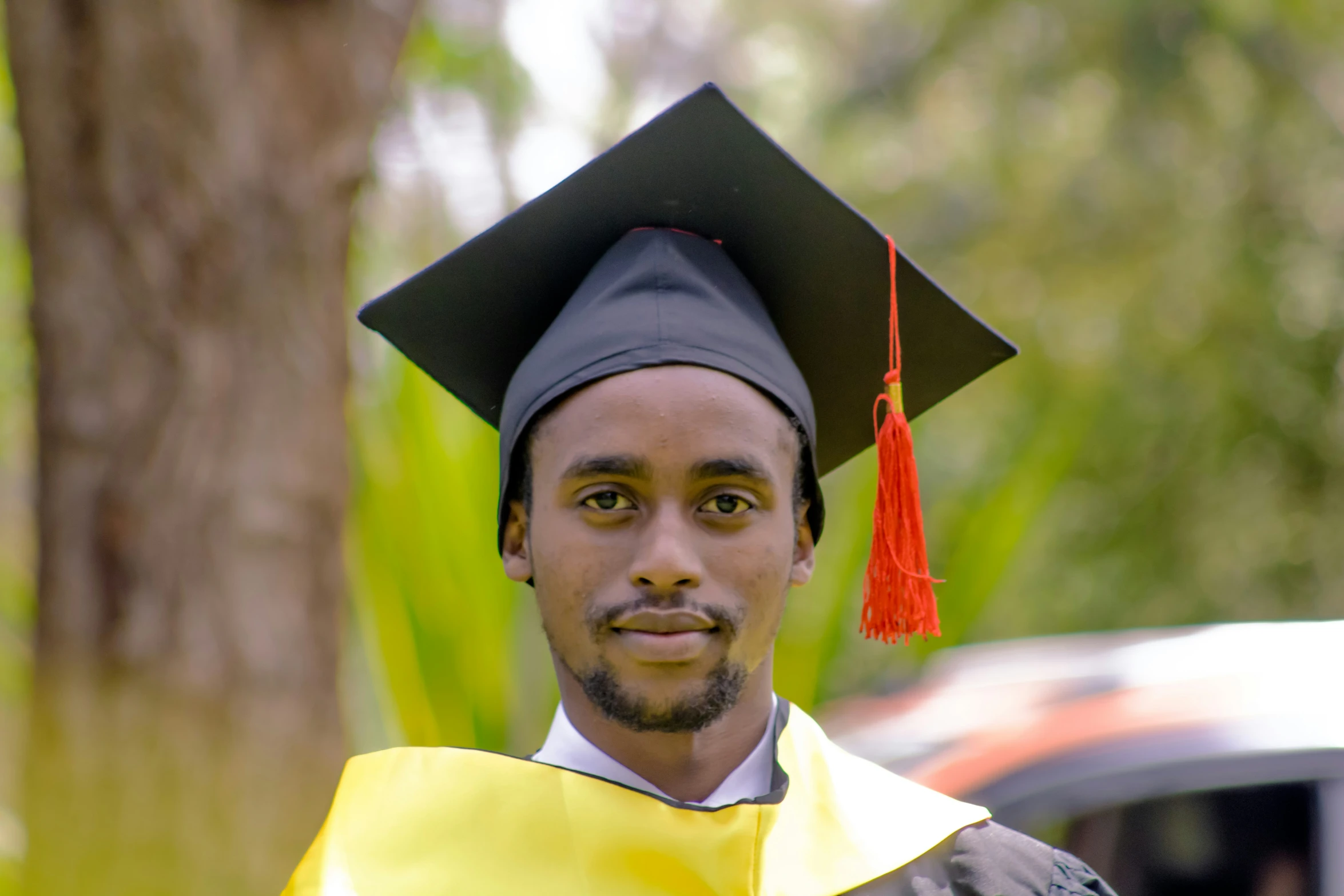 man in a black hat, gown and gown, looking to camera