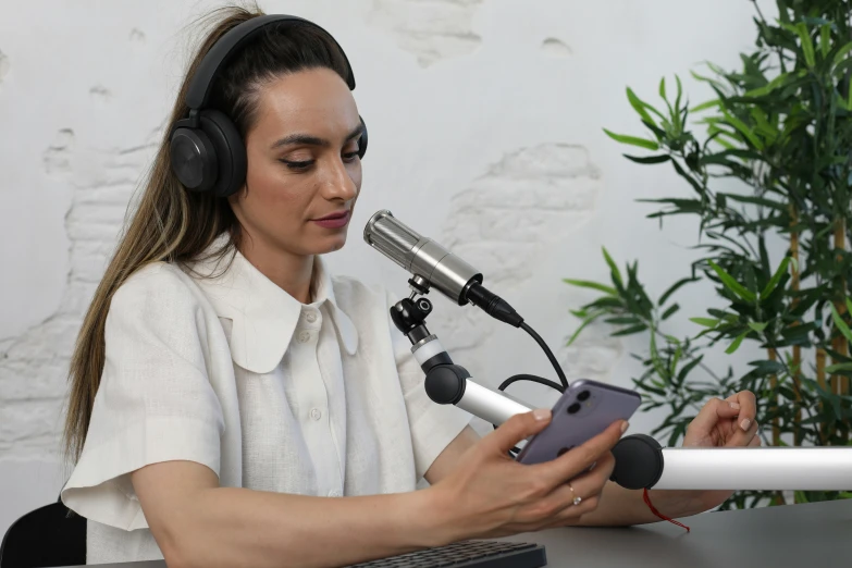 woman wearing headphones sitting in front of microphone and tablet