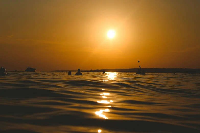 people paddling their boats across the water at sunset