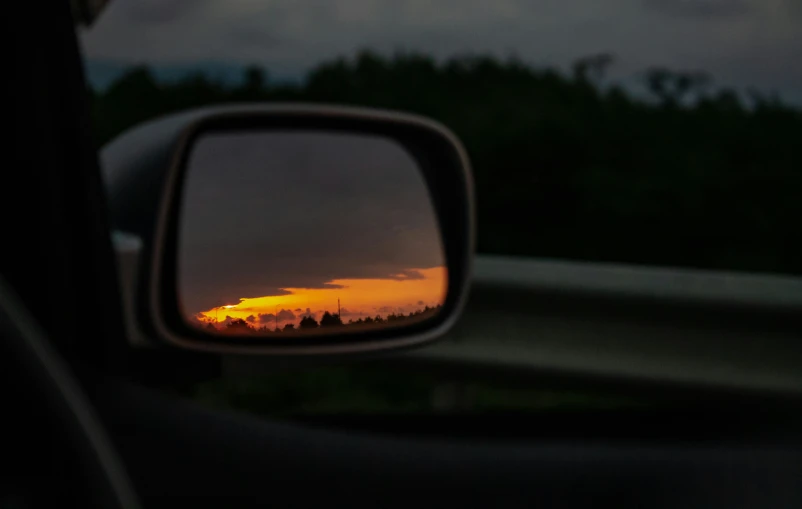 the sun is setting in the back window of a car