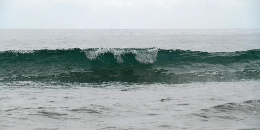 the ocean is blue and has a wave coming towards shore