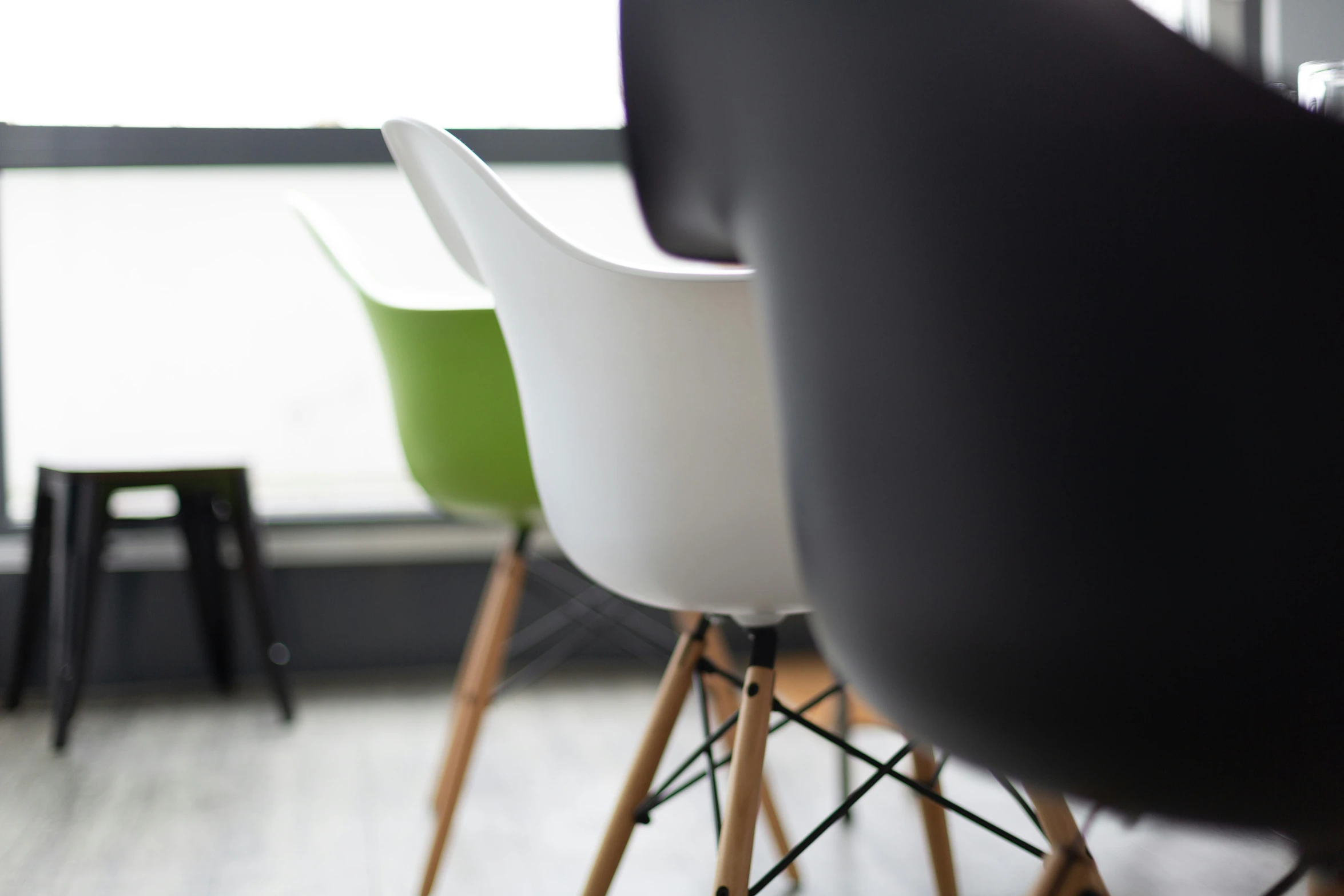 two different colors of chairs with legs and legs in front of a window