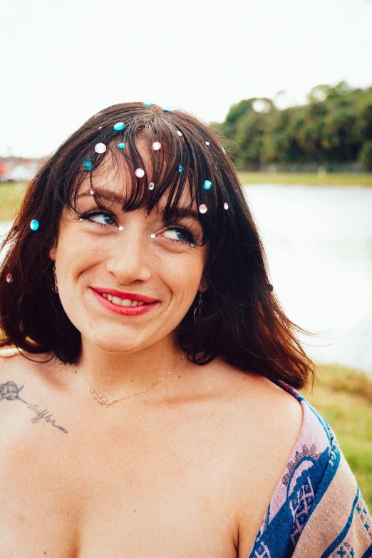a woman with blue hair and a string of colored beads is smiling