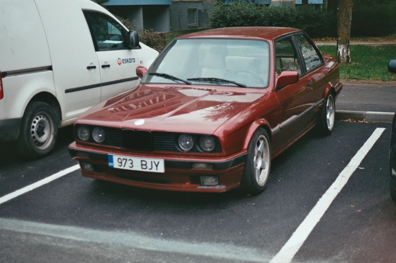 a maroon car parked in a parking space next to a white van