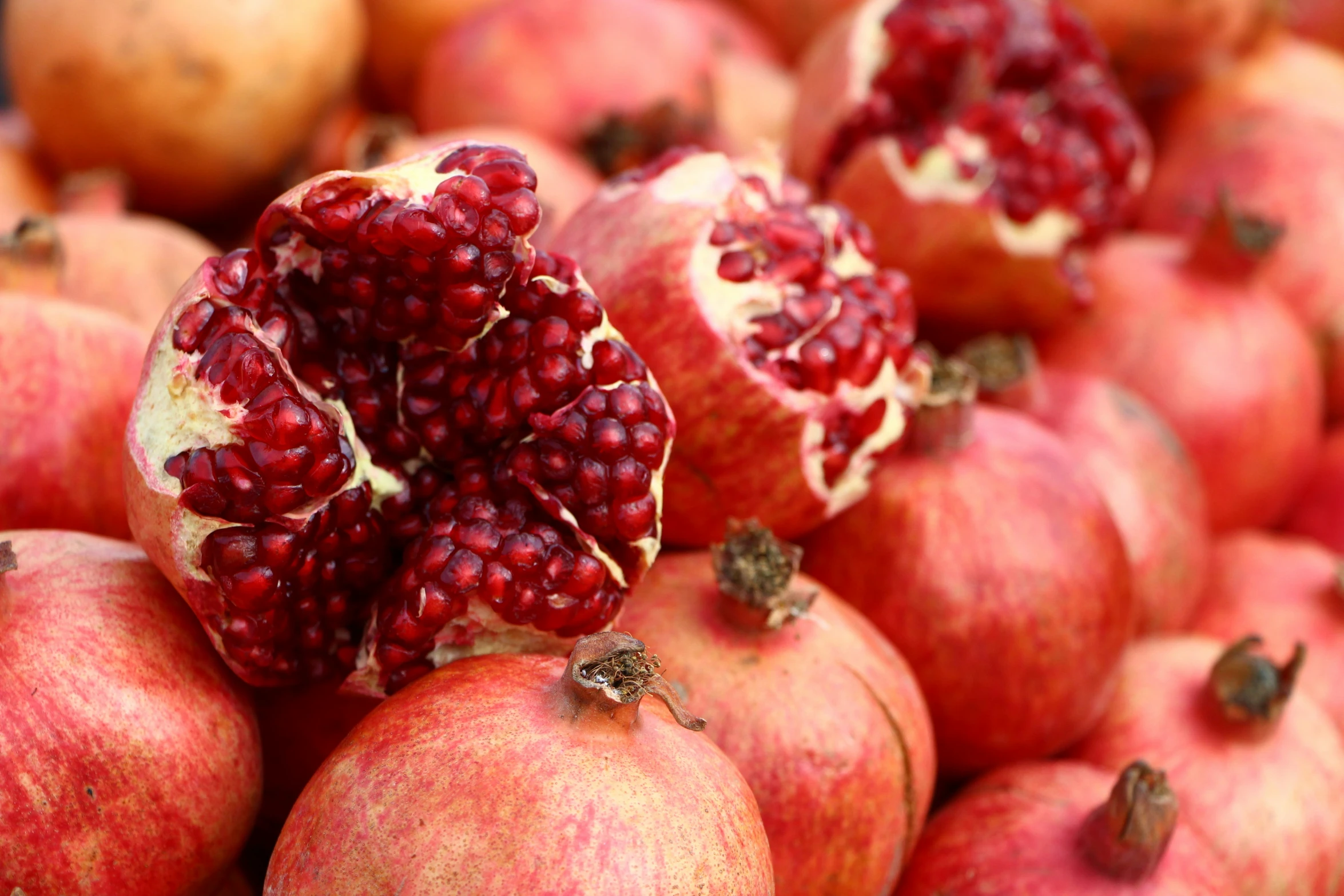 pomegranates are stacked on top of each other in a pile