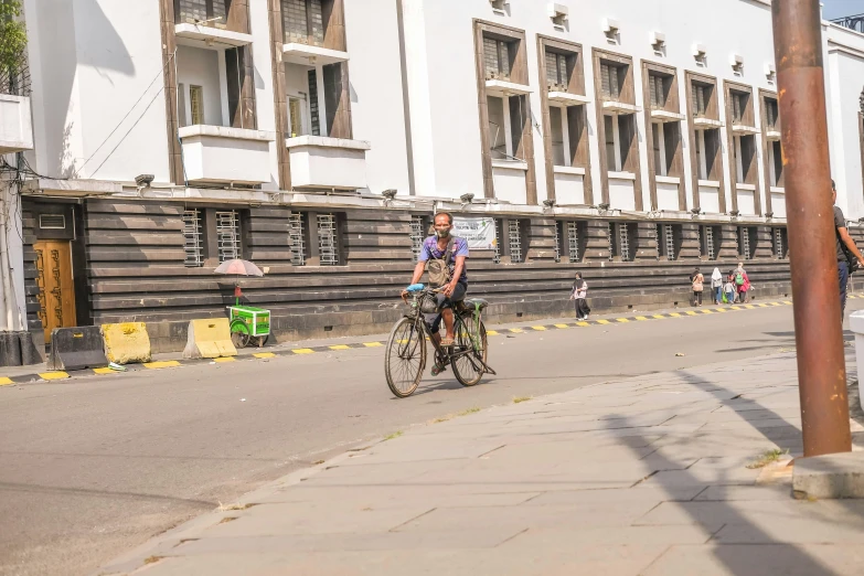 two men riding bikes down the street with buildings in the background