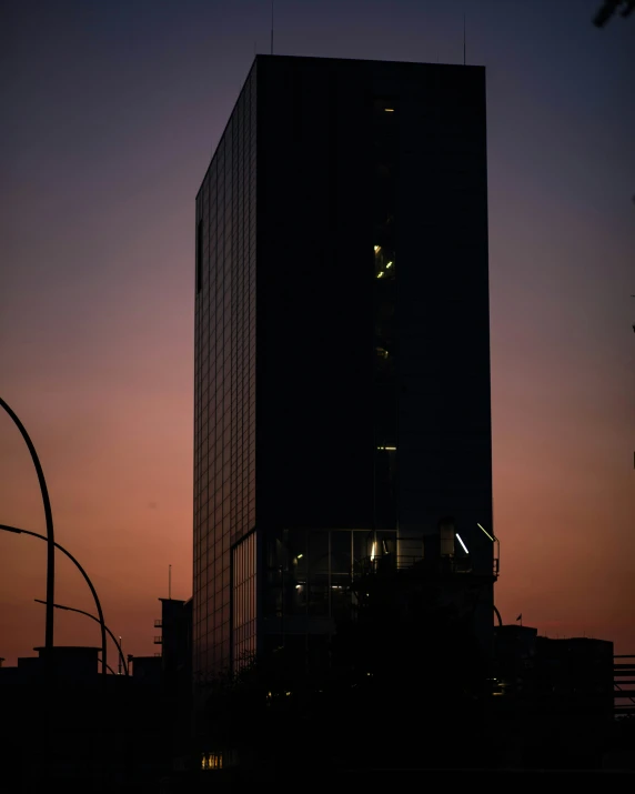 the silhouette of a building at dusk in front of a city street