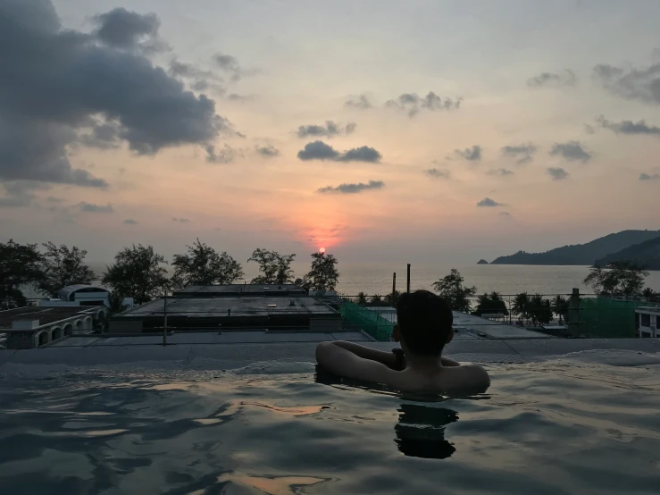 woman laying on back of  tub looking at sunset