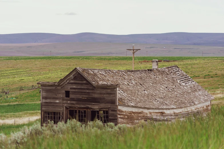 an old farmhouse with a cross on top in the middle of the countryside